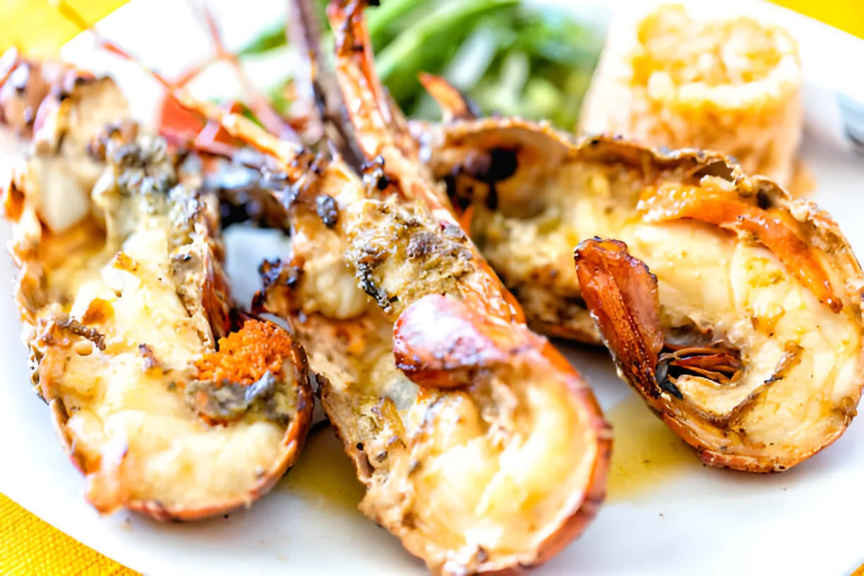 Grilled lobster tails served on a plate with lemon wedges and a sprinkle of parsley.
