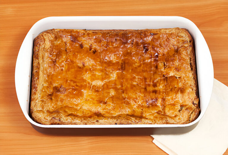 Golden-brown baked pastry in a white dish on a wooden table