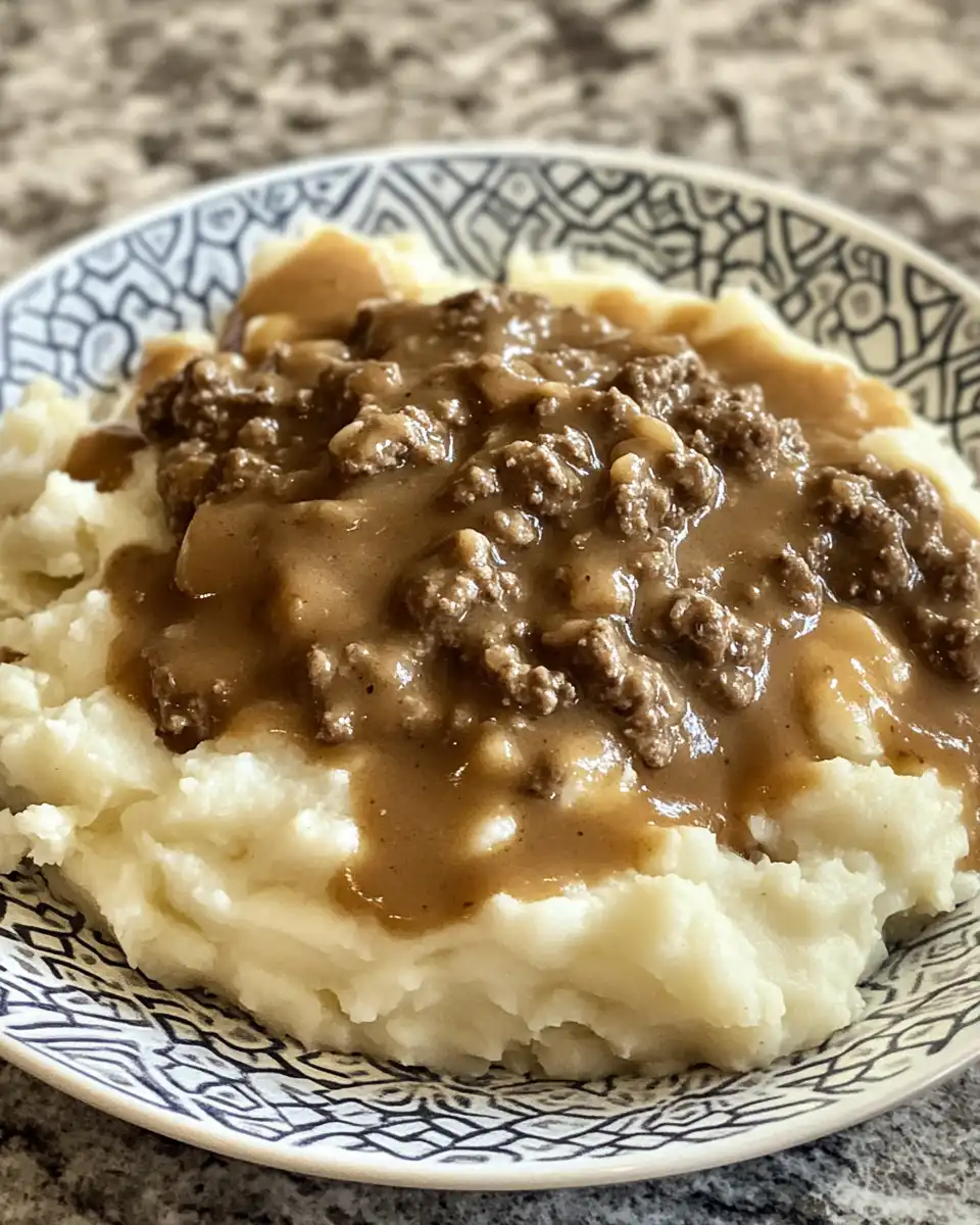 Finished plate of ground beef and rich gravy over mashed potatoes, ready to eat