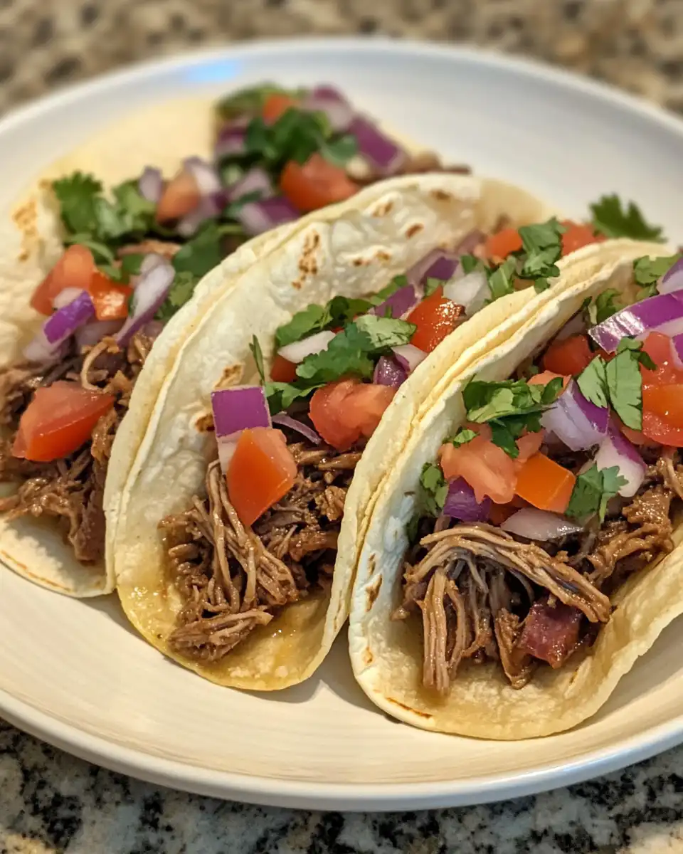 Close-up of pressure cooker pulled beef in warm tortillas with toppings