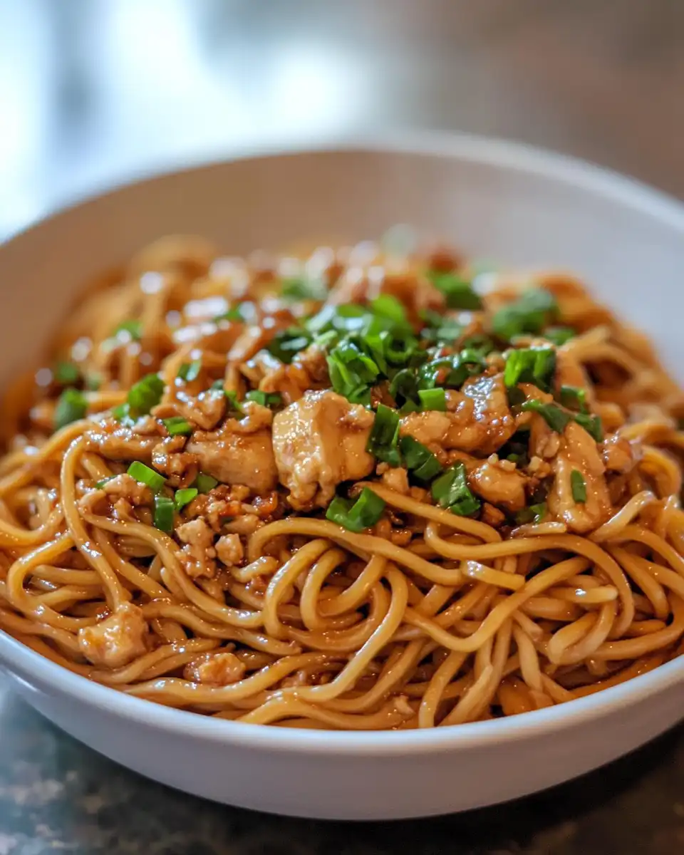 Sticky garlic chicken noodles finished and garnished with scallions and peanuts